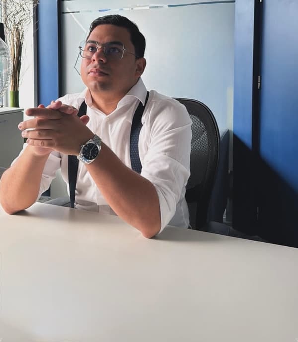 Alejandro Casares Bruno, asesor inmobiliario en Madrid, sentado a una mesa de despacho con camisa blanca y tirantes